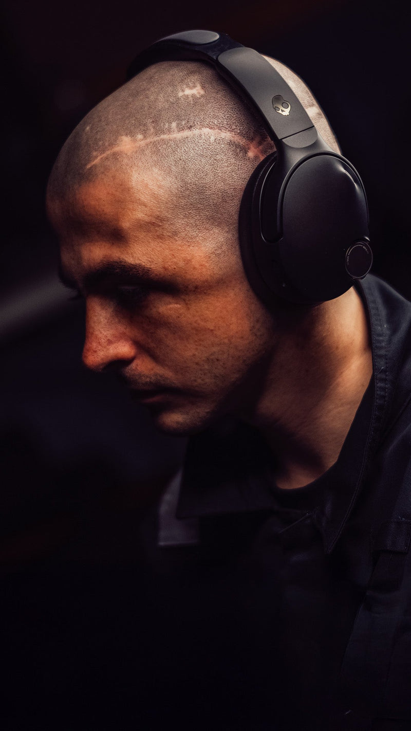 Man wearing black headphones in a dark setting