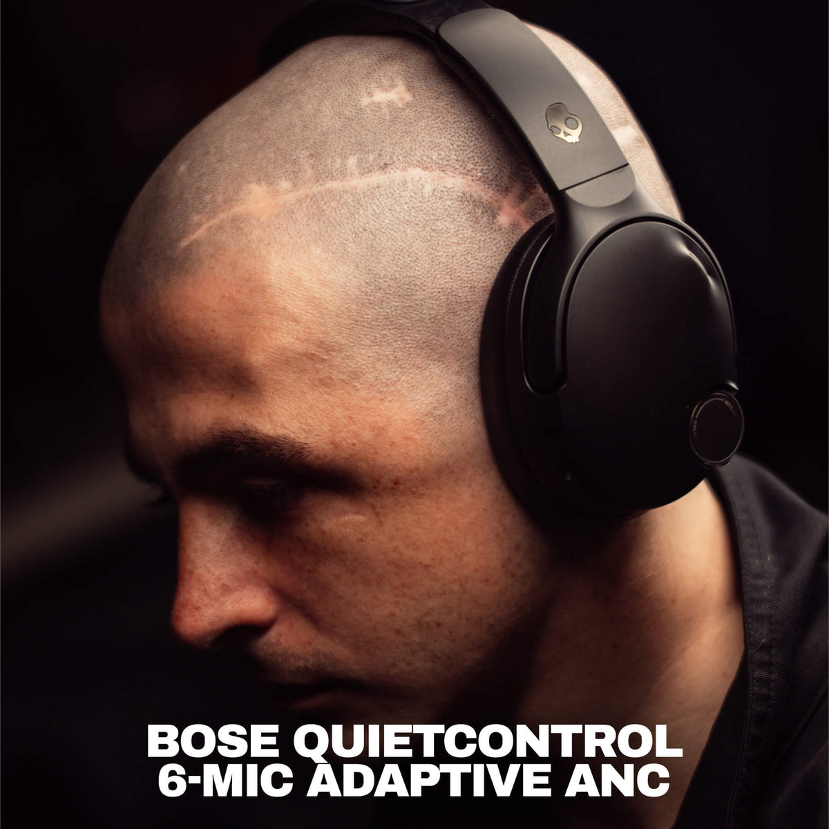True Black | A close-up of a man wearing black Crusher 1080 headphones with Bose QuietControl 6-Mic Adaptive ANC over-ear headphones against a dark background, with bold white text at the bottom reading 'BOSE QUIETCONTROL 6-MIC ADAPTIVE ANC'.
