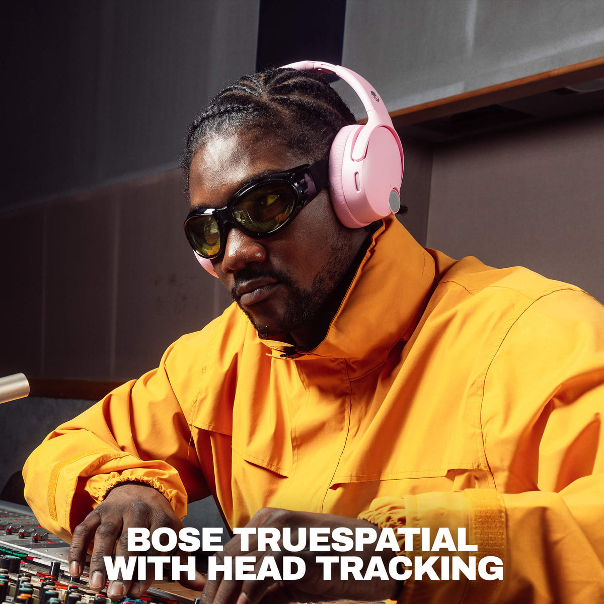 Candy | A man in a recording studio wearing pinkSkullcandy Crusher 1080 headphones with  Bose TrueSpatial headphones with head tracking, a bright yellow jacket, and dark sunglasses, with the text 'BOSE TRUESPATIAL WITH HEAD TRACKING' at the bottom.