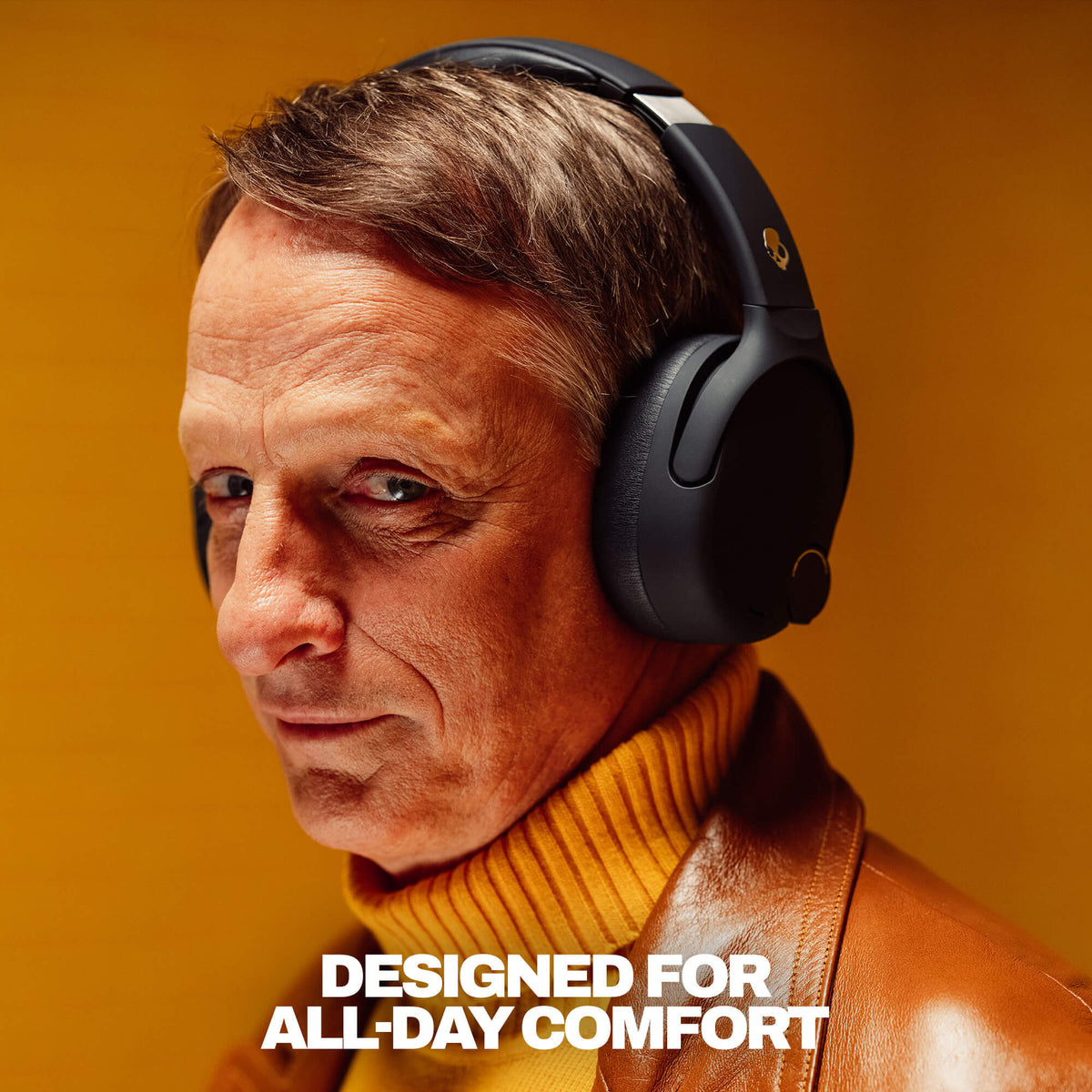 True Black | Tony Hawk wearing Crusher 720 over-ear headphones with an orange background with title 'Designed for All-Day Comfort"