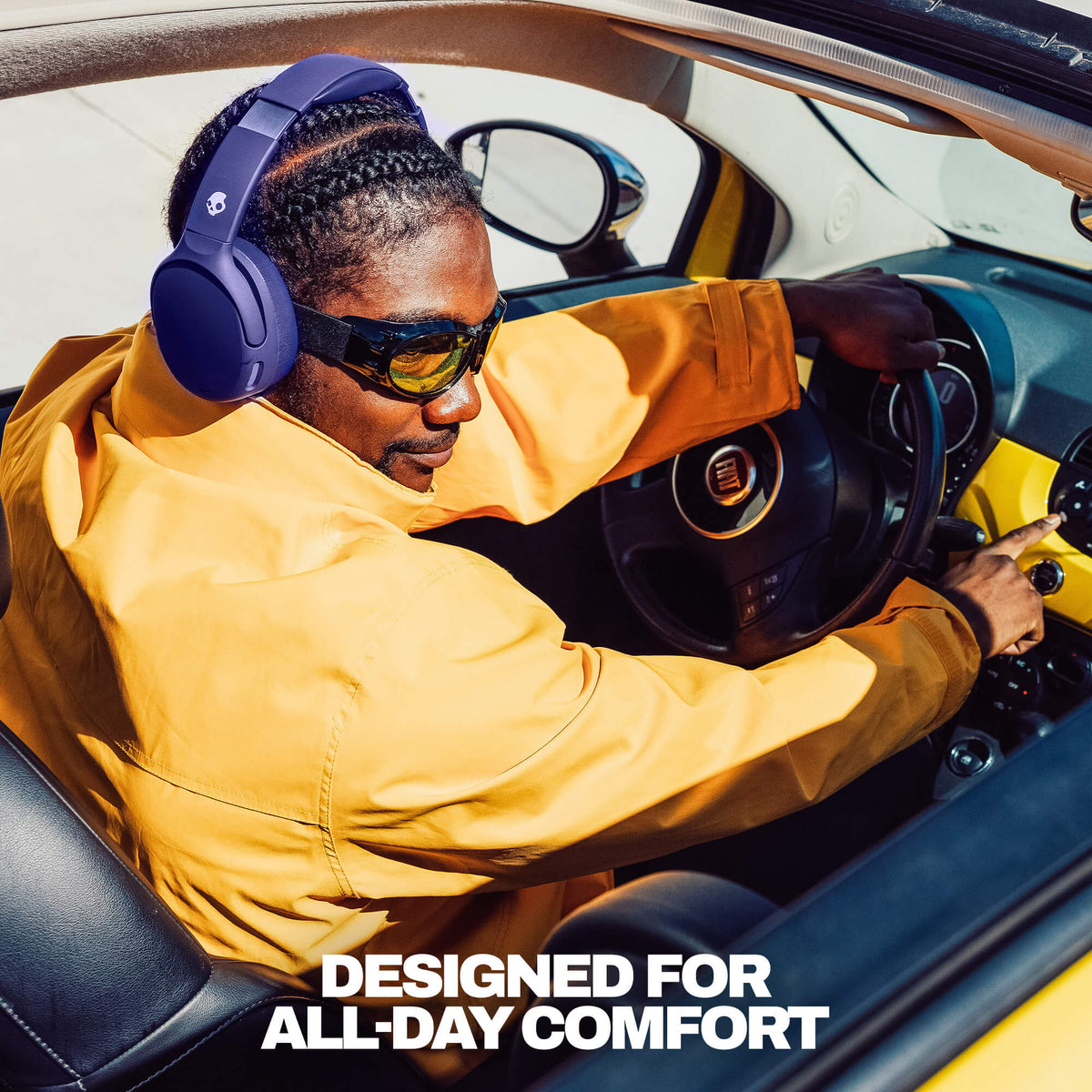 Future | A man wearing Crusher 720 deep blue over-ear headphones and sunglasses sits in the driver's seat of a convertible car, in a mustard yellow jacket. The text 'DESIGNED FOR ALL-DAY COMFORT' is displayed at the bottom.
